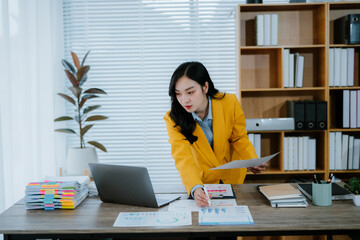 Asian businesswoman working with laptop in coworking space. Beautiful female freelance writer...
