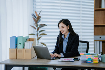 Beautiful Asian businesswoman typing on laptop computer while working in the modern office room.