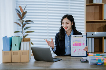 Beautiful Asian businesswoman typing on laptop computer while working in the modern office room.