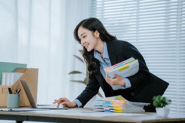 Smiling Young asian accountant business woman working with documents using calculator and laptop...