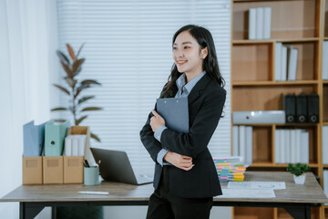 Asian businesswoman standing holding a file looking at you with a happy smile