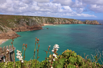 Scenic view from overlooking Porthcurno Beach, Treryn Dinas and Logan Rock, Cornwall; turquoise...