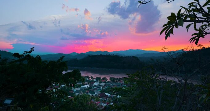  Sonnenuntergang &uuml;ber Luang Prabang in Laos zur goldenen Stunde, tief stehende Sonne hinter dem Mekong und den Bergen, atmosph&auml;rischer Blick mit Stadtanschnitt in tropischer H&uuml;gellandschaft