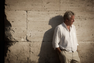 portrait of person standing against ancient wall bathed in warm tones