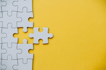 Obraz premium Missing puzzle piece on yellow background problem solving teamwork connection concept with copy space.