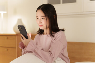 夜中にスマホを見る女性