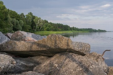 Calm river landscape with forest bank, blue sky and calm water in summer