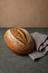 A fresh artisan loaf of bread on a rustic table, beside a linen cloth. The bread's crust is a beautiful golden-brown, and its warm, inviting aroma fills the air