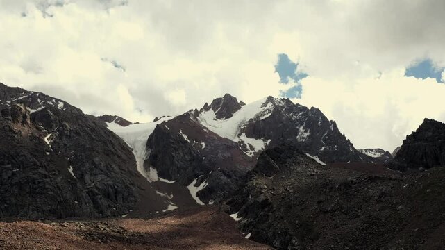Timelapse of flying clouds over high mountains with rocks and glaciers. Zailiyskiye Alatau ridge in the Tien Shan mountain system in Kazakhstan in the city of Almaty views from the Talgar pass