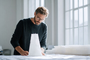 Architect designing a modern building model, bathed in natural light. Conceptual for innovation, planning, and craftsmanship. Ideal for construction and design.