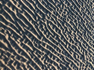 gray beach wavy sand ripples dune texture wallpaper pattern background close-up