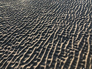 gray beach wavy sand ripples dune texture wallpaper pattern background close-up
