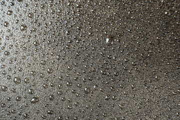 Water droplets on a cast iron macro surface. Cast iron cookware care, rust resistant, abstract pattern