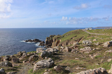 Obraz premium Scenic view of rocky Cornish coastline at Land’s End with 'First and Last House in England' seen overlooking the Atlantic Ocean