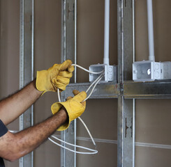 
Electrician working with gloves on indoor wiring installation