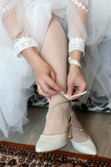 The bride's friend helps her put on her shoes.
