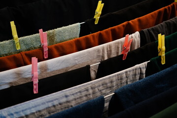 Colorful clothespins secure freshly washed fabrics on a vibrant drying line in a cozy indoor...