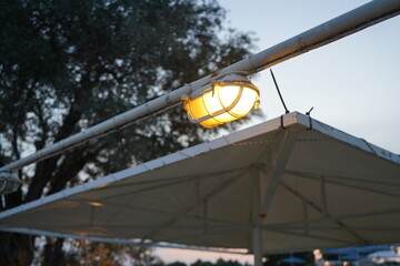 Soft glow of a rustic lamp under a white canopy as dusk approaches, setting a serene atmosphere for...