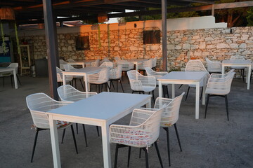 Evening tranquility unfolds as empty tables invite guests for a delightful dining experience under the warm glow of sunset in a serene outdoor setting
