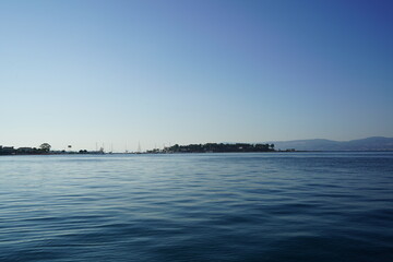 Ocean view at dawn with distant hills and boats in the calm waters of a tranquil seaside town