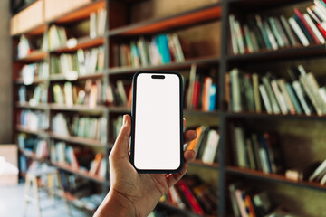 Smartphone with blank white screen mockup held in hand, with a blurred library background. Perfect...