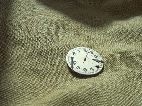 Old watch face part on olive fabric  - Powered by Adobe