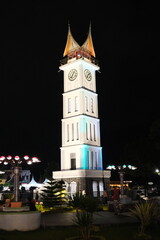 Iconic Jam Gadang clock tower illuminated at night in Bukittinggi, West Sumatra, surrounded by...