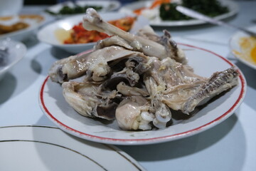 Classic West Sumatran dish Ayam Pop featuring lightly fried chicken with pale skin, served on a plate among various side dishes.
