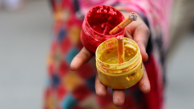 Mini box of red and yellow chandan used by local vendors outside temples for applying tilak to devotees during parikrama in Govardhan, a traditional and regional spiritual practice