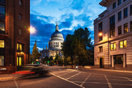 Illuminated St. Pauls Cathedral viewed from a London street with passing car lights at dusk