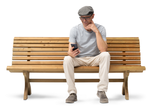Smiling mature man in his 50s sitting on a park wooden bench and using a smartphone. Studio shot, isolated on white background. Casual clothing, wearing reading glasses and a hat