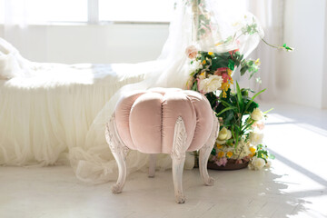 Pink velvet padded stool with wooden legs in classic bedroom. Shabby chic interior girly or...
