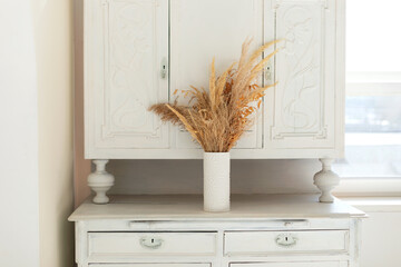 On the buffet stands vase with bouquet dried flowers and grass. Vintage retro style. Rustic fall...