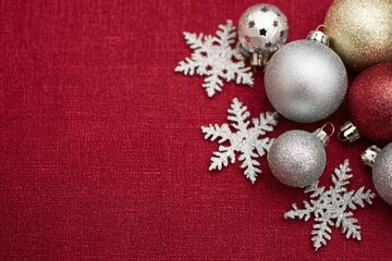A collection of silver and gold baubles adorned with white snowflakes rests on a vibrant red backdrop, evoking the spirit of holiday cheer