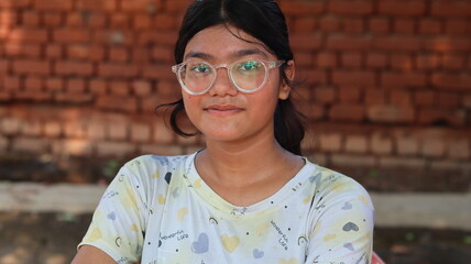Portrait of a young Indian girl wearing spectacles, looking directly at the camera with a calm...