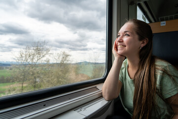 Mujer feliz y sonriente mirando por la ventana durante su viaje en tren