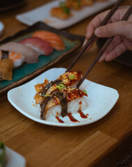 Unagi Sushi with Chopsticks. A close-up shot of delicious unagi (eel) sushi being held with chopsticks, presented on a white plate.