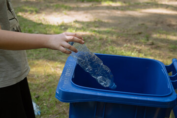 children clean up the forest by throwing empty bottles into a bag and a trash can