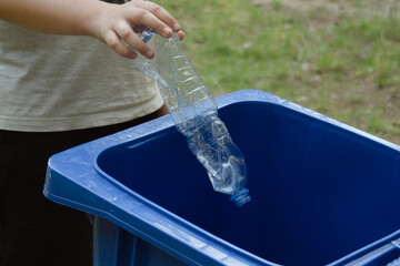 children clean up the forest by throwing empty bottles into a bag and a trash can