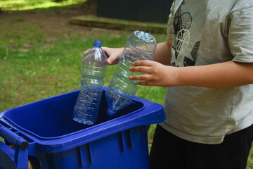 children clean up the forest by throwing empty bottles into a bag and a trash can