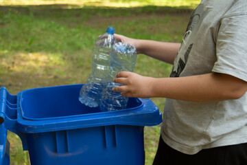 children clean up the forest by throwing empty bottles into a bag and a trash can