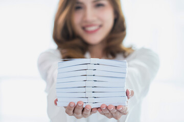 Smiling Southeast Asian woman showing a fan of US dollar banknotes with both hands. Concept of...