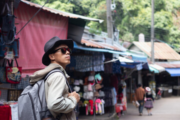 Obraz premium Male tourist wearing hat walking through open air market exploring village, shopping, sightseeing, community, tradition, goods, discovery, photography, transportation, travel scene