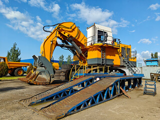 Large yellow excavator with a powerful digging arm, positioned on a construction site, surrounded...