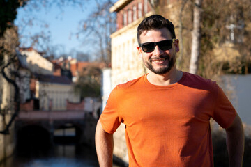 Turista sonriente disfrutando de un paseo soleado junto a un canal en Praga. Hombre apuesto sonré al aire libre