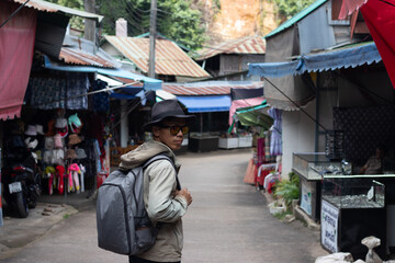 Fototapeta premium Male tourist wearing hat walking through open air market exploring village, shopping, sightseeing, community, tradition, goods, discovery, photography, transportation, travel scene