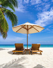 Fototapeta premium Tropical Beach Relaxation: Two wooden lounge chairs sit under a large beach umbrella on a pristine white sand beach, with a palm tree in the background. The ocean is calm and clear.