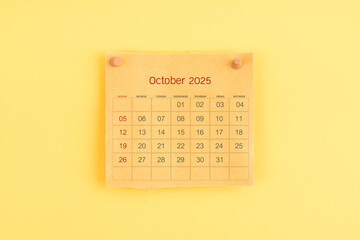 October 2025 brown calendar with wooden thumbtack on yellow color background.