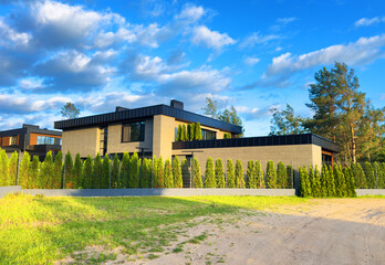 Villa with Fence from thuja. Thuja fence at Villa Prefab house. Luxury Modern house. Elite Home Exterior, suburban house. Fence made of Thuja. Privacy screen or a dense hedge from evergreen trees.