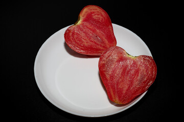Heart shaped tomato isolated on white plate.
Round pink red tomato with a nose that forms a heart...